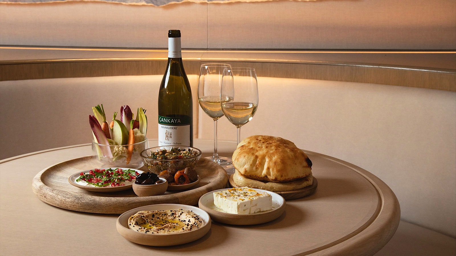 A table at Iris, featuring various small plates, flatbreads, crudite, and a bottle of white wine with two glasses.